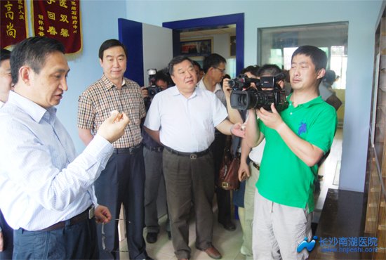 在结石专家诊室结石标本墙前，龚建明常委饶有兴致地拿起一瓶我院留存的结石标本
